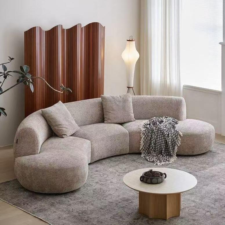 Rounded Beige Chaise Sofa with Soft Barrel Arms and Plush Pillows